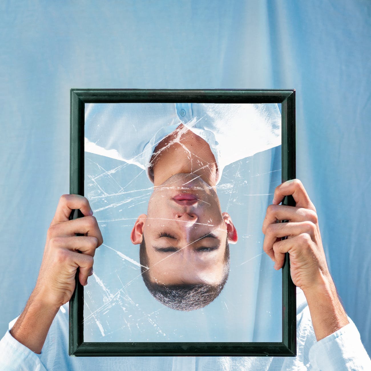 man closing his eyes reflection on mirror